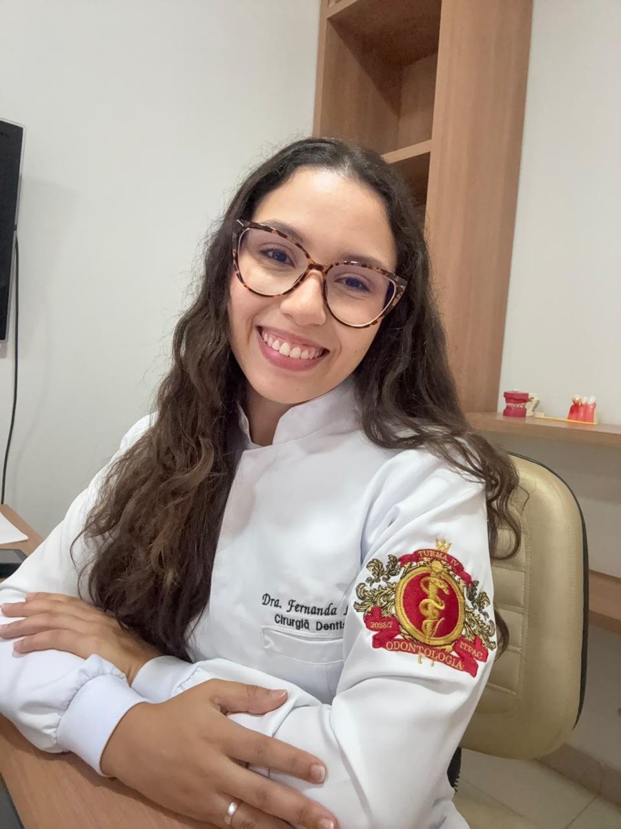 Dra. Fernanda Labre Martins de jaleco, sorrindo, no consultório